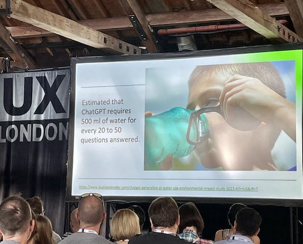 Photo of a slide on a large screen. Text on the left says, "Estimated that ChatGPT requires 500 ml of water for every 20 to 50 questions answered". On the right a picture of a child, aged 7 or 8, drinking water from a green drinks bottle.